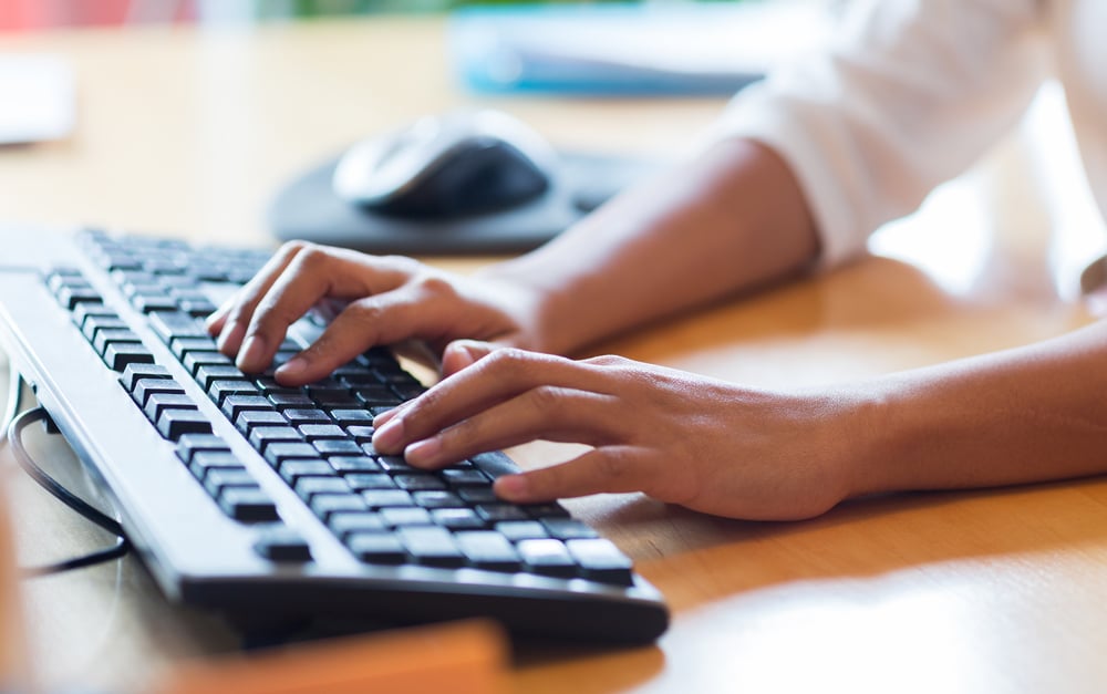 Fingers typing on keyboard in assertive brand voice