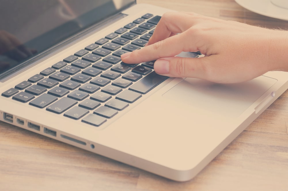 Someone's hand pressing a button link on their laptop.